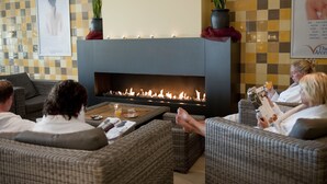 Un área de descanso con chimenea, muebles de mimbre y un estampado de pared a cuadros.