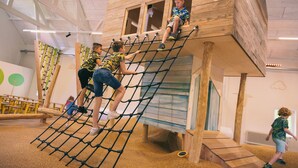Una estructura de juego de madera con redes para escalar y un tobogán.