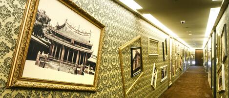 A hallway with patterned wallpaper and framed pictures on the walls.