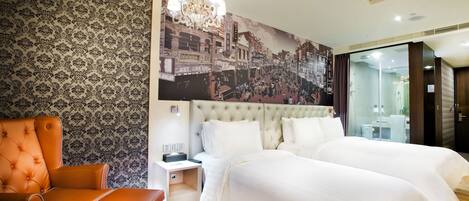 A hotel room with a large bed, a chair, a nightstand, and a wall mural.