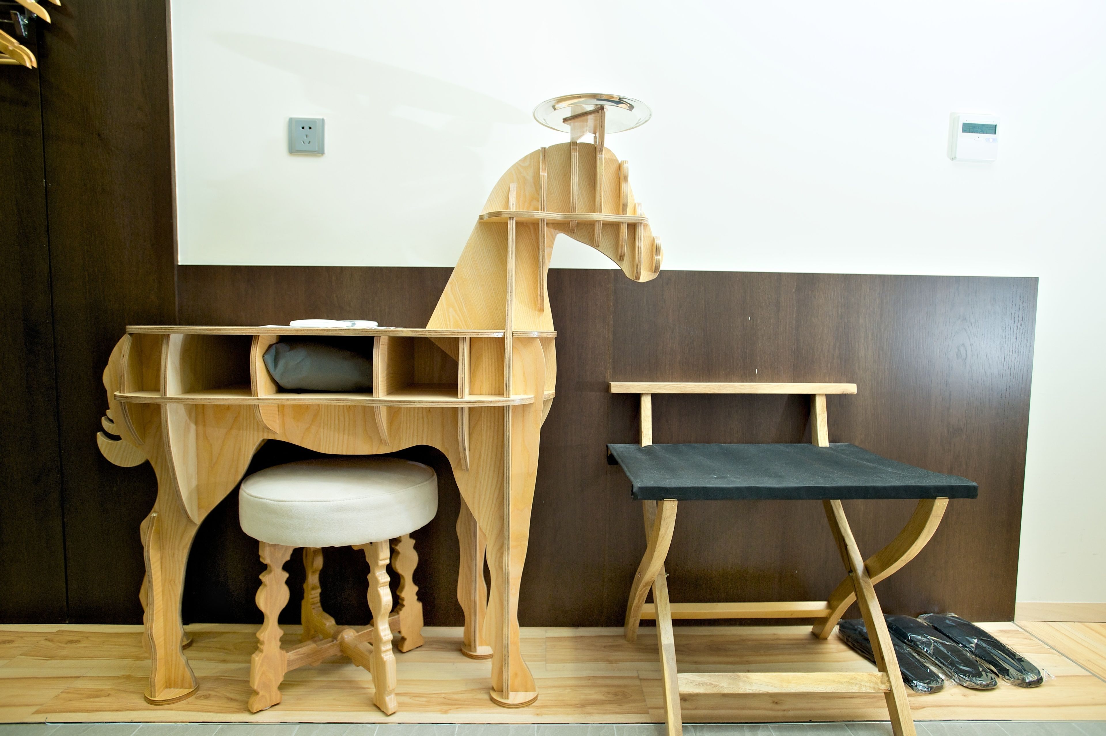 Ein Holzpferd-Schreibtisch mit gepolstertem Sitz und einem separaten schwarzen Tisch.