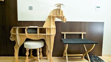 A wooden horse-shaped desk with a cushioned seat and a separate black table.