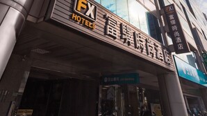 A hotel building with a prominent FX logo, large glass windows, and a modern architectural design.