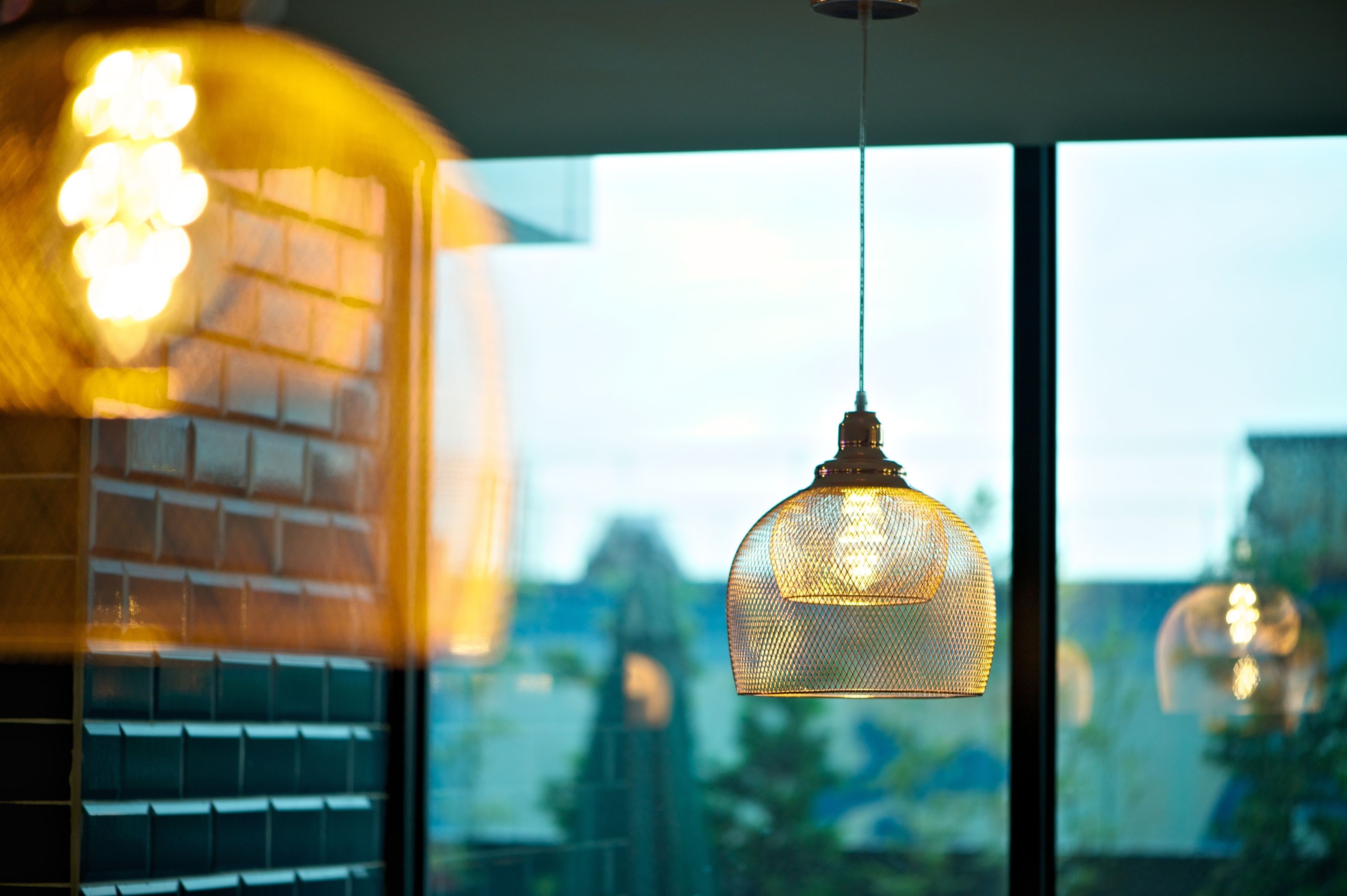 A modern interior with a hanging pendant light and a view of a cityscape through large windows.