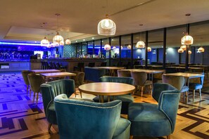 A restaurant with round tables and blue upholstered chairs, a bar area with a blue-lit counter, and hanging pendant lights. - FX Hotel Tainan MinSheng Road Branch (Tainan)