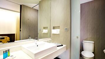 Un baño moderno con un espejo grande, un lavabo blanco y un inodoro.
