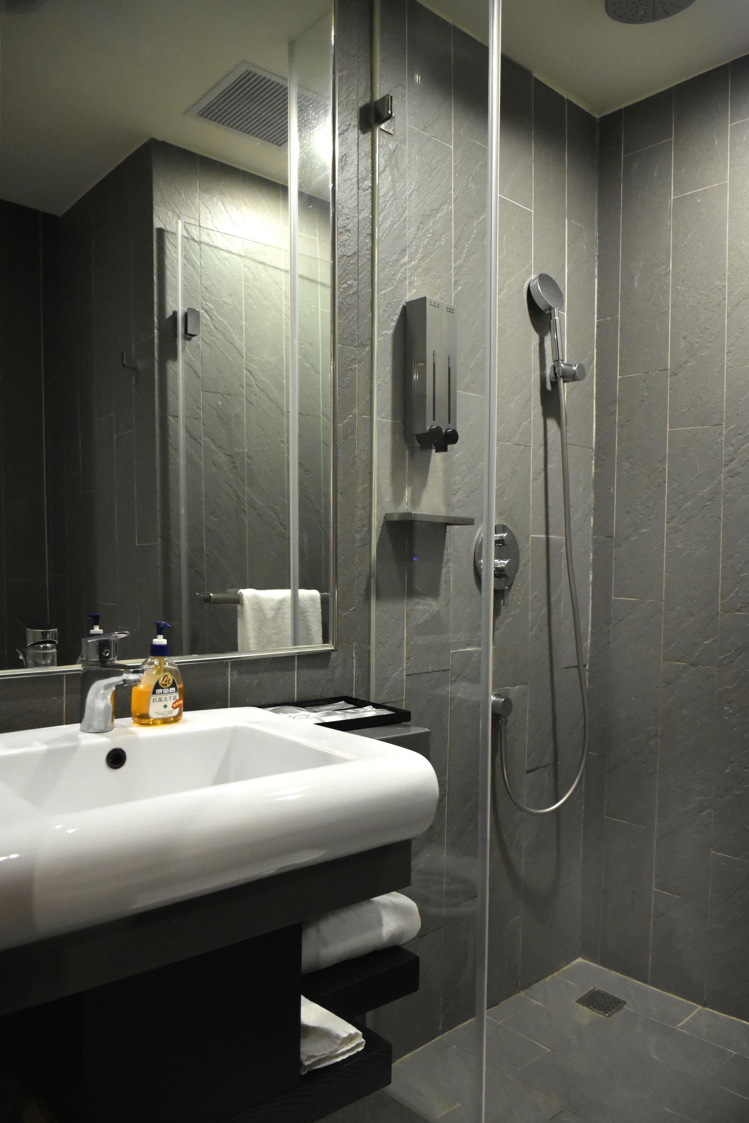A modern bathroom with a glass-enclosed shower, a white sink, and a mirror.