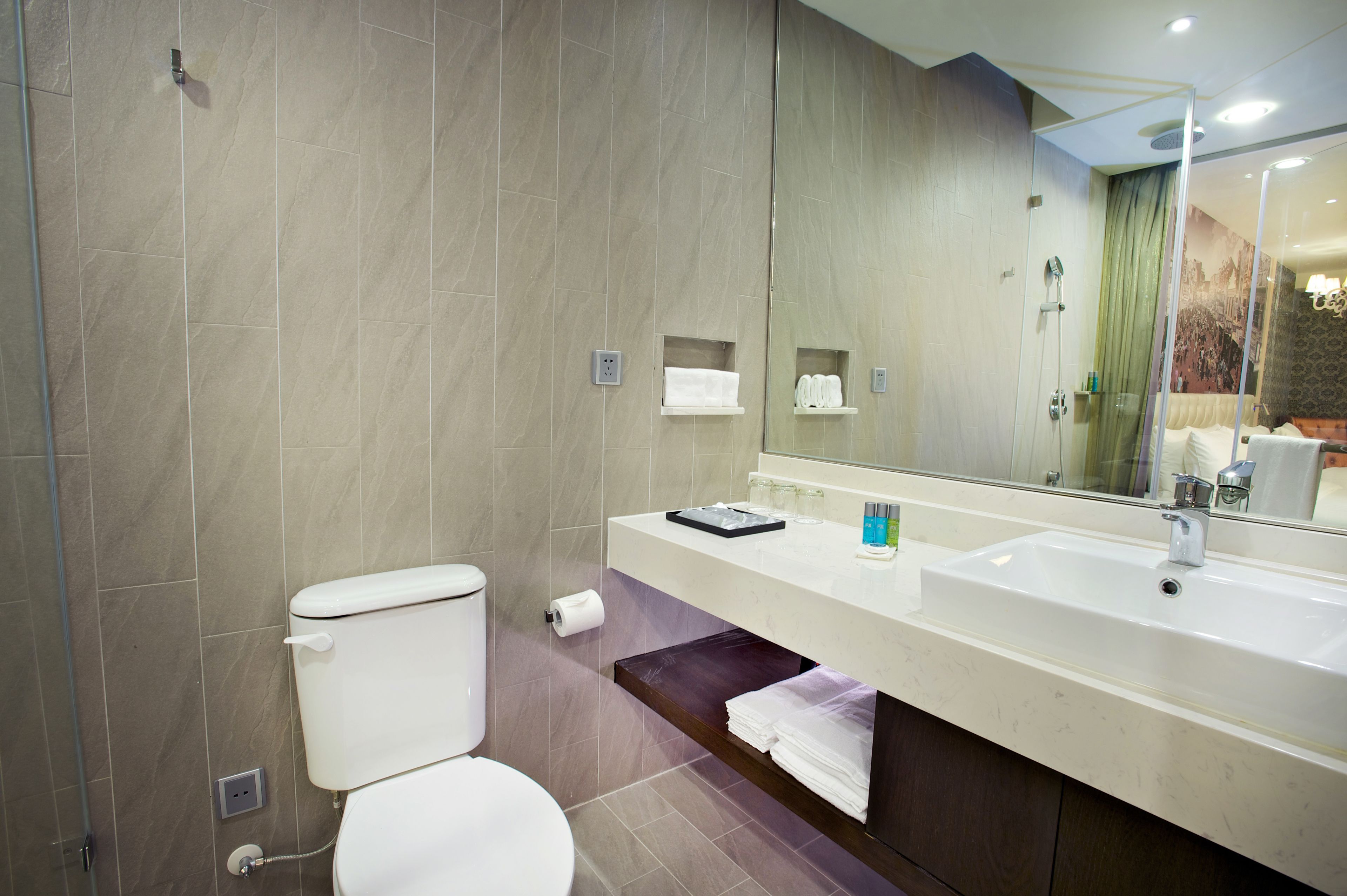A modern bathroom with a toilet, sink, and mirror.