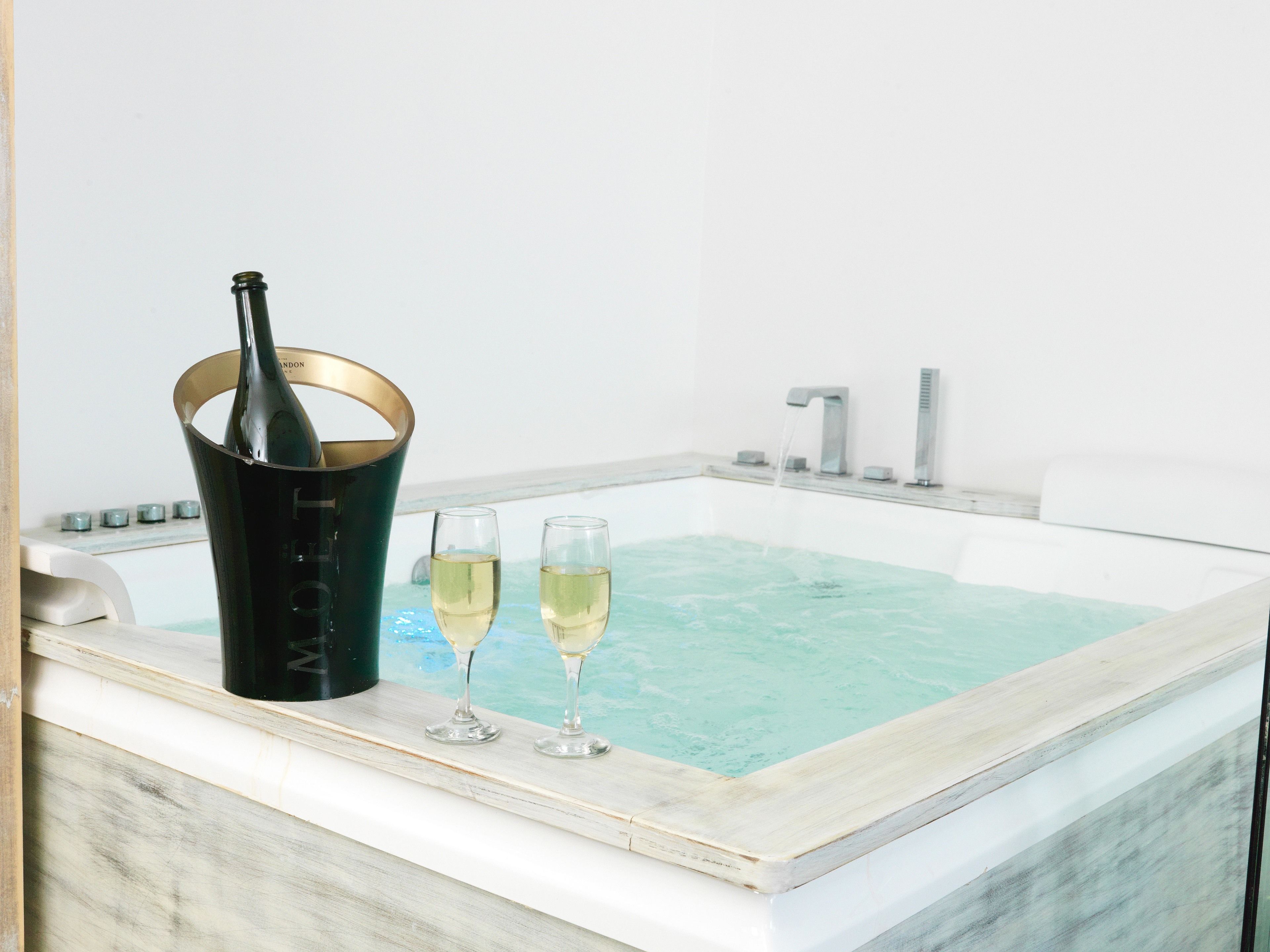 Un jacuzzi con una botella de champán y dos copas.