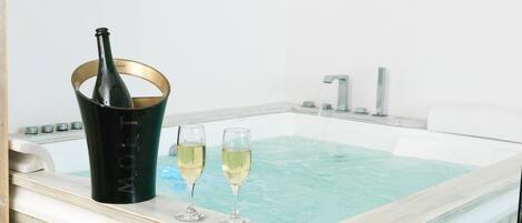 Un jacuzzi con una botella de champán y dos copas.