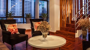 A modern interior with a round table, two chairs, and a staircase.
