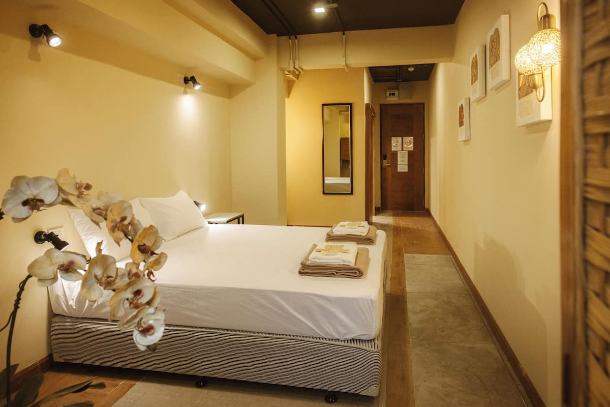 Una habitación de hotel con una cama, un espejo y un pasillo que conduce a otra habitación.