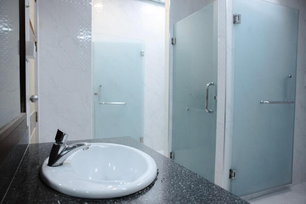 A bathroom with a white sink, a glass shower enclosure, and a frosted glass door.