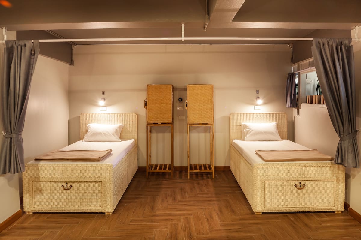 Una habitación con dos camas individuales, cada una con cabecera y mesita de noche.