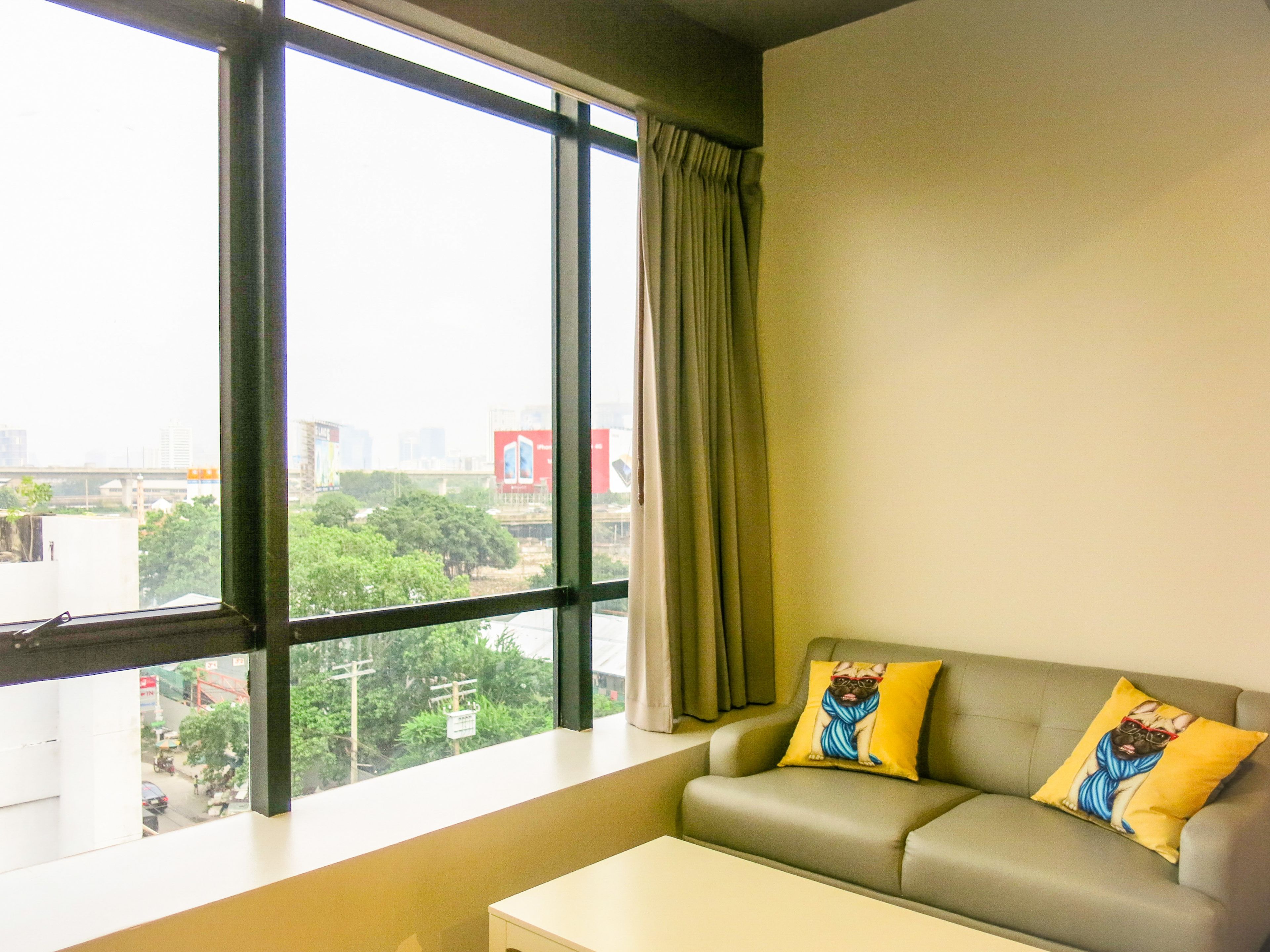 A room with a sofa, a window, and a view of a cityscape.