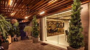 An outdoor area with potted plants, a ceiling fan, and a modern interior visible through glass doors.