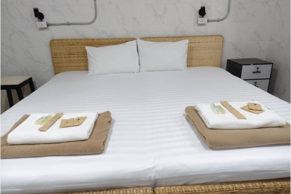 Un lit bien fait, avec des draps blancs et deux serviettes marron pliées posées sur le dessus.