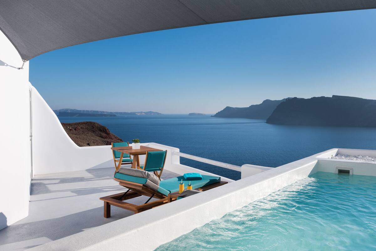 Un área junto a la piscina con vistas al mar y un paisaje montañoso.