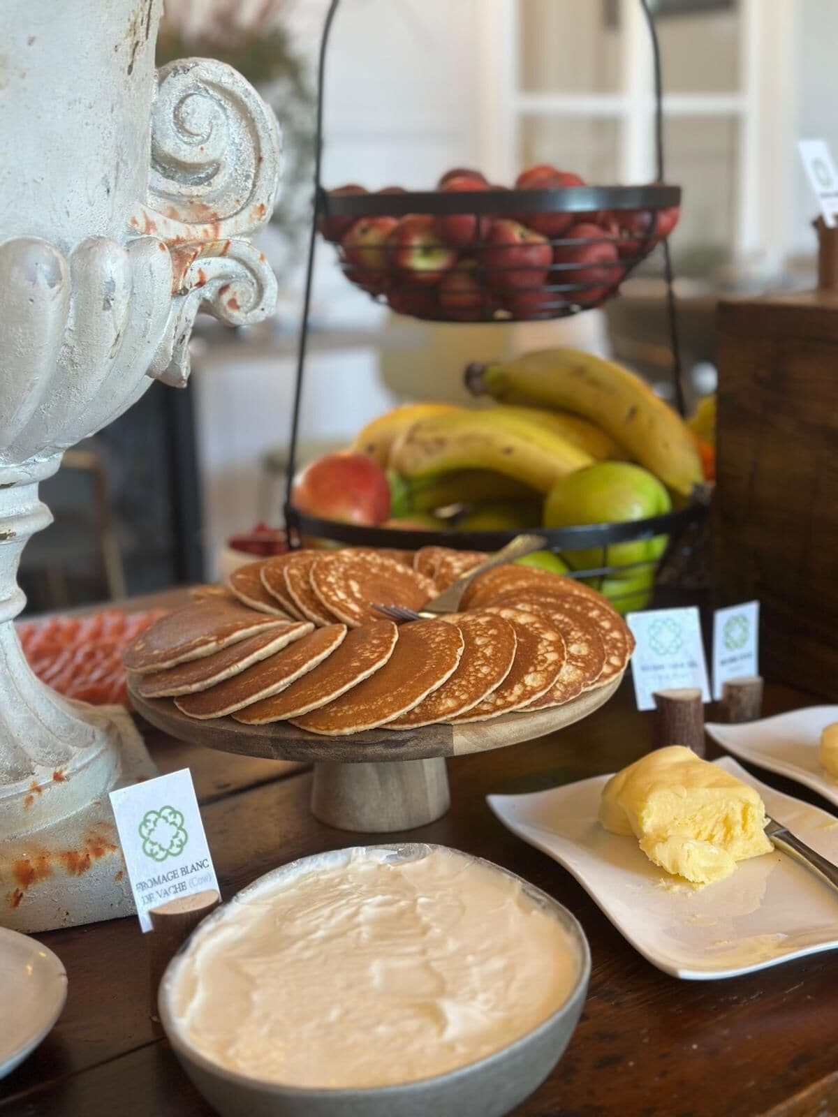 Een buffet met pannenkoeken, fruit en een kom room.