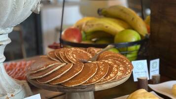 Een buffet met pannenkoeken, fruit en een kom room.