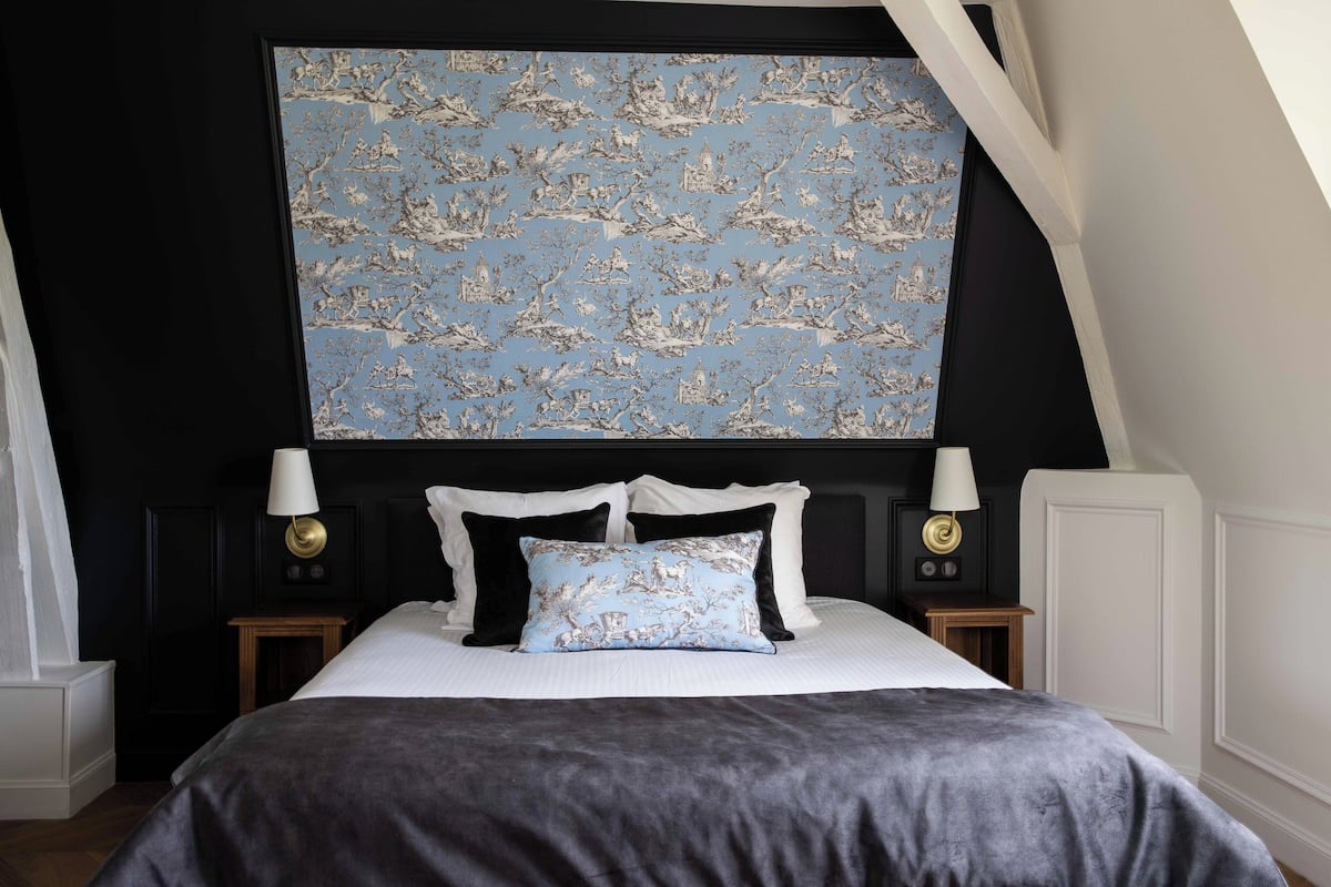 A bedroom with a large bed, two bedside tables, and a wall-mounted artwork.