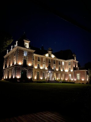 A large, illuminated historic building with multiple windows and a prominent entrance.