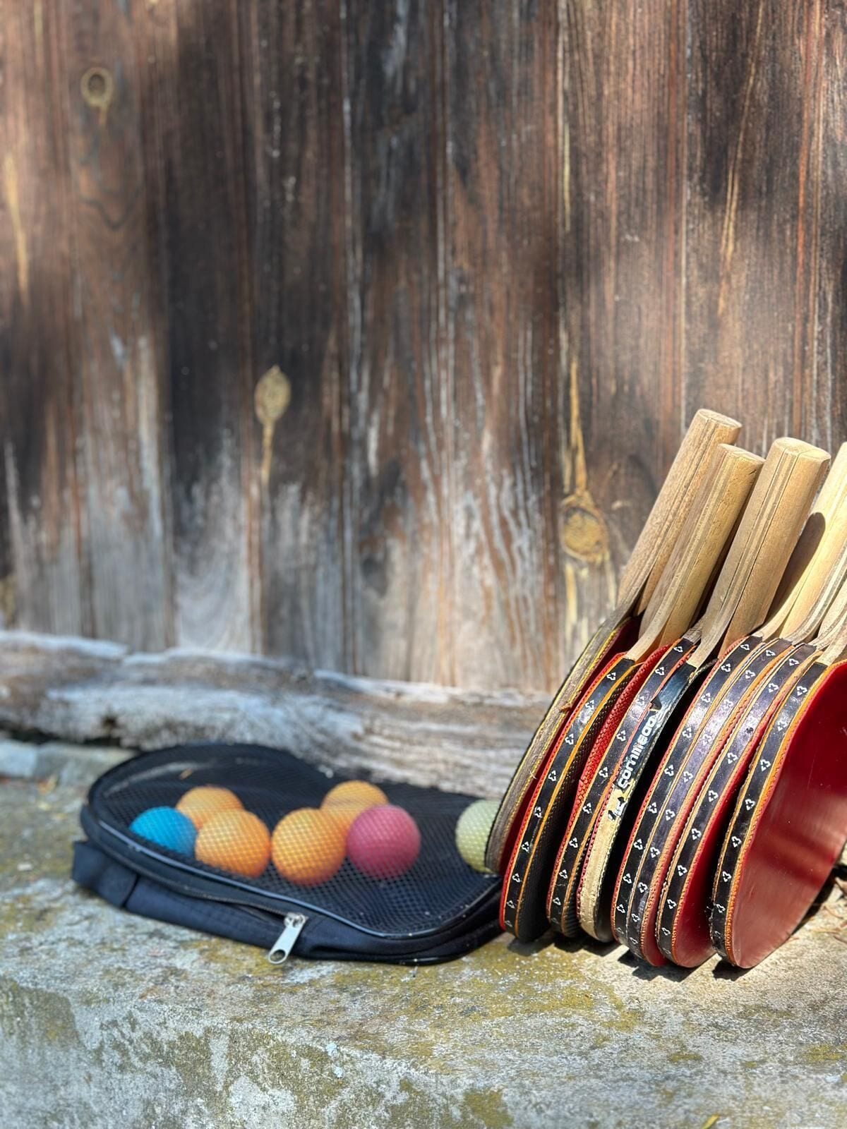 A collection of colorful balls and wooden sticks on a stone surface with a wooden background.