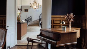 Una sala amplia con un piano, un escritorio y una araña.