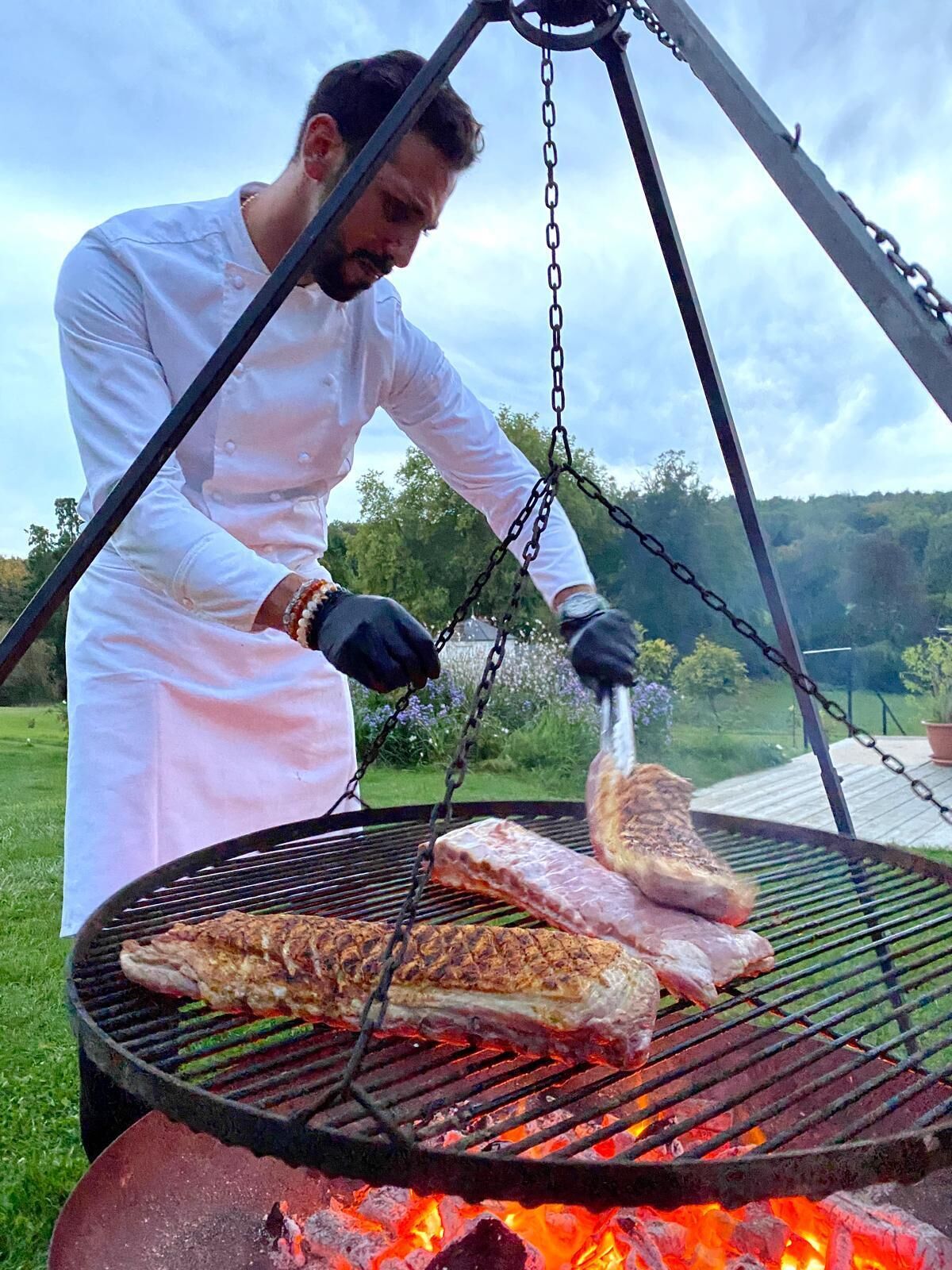 A person grilling meat outdoors.