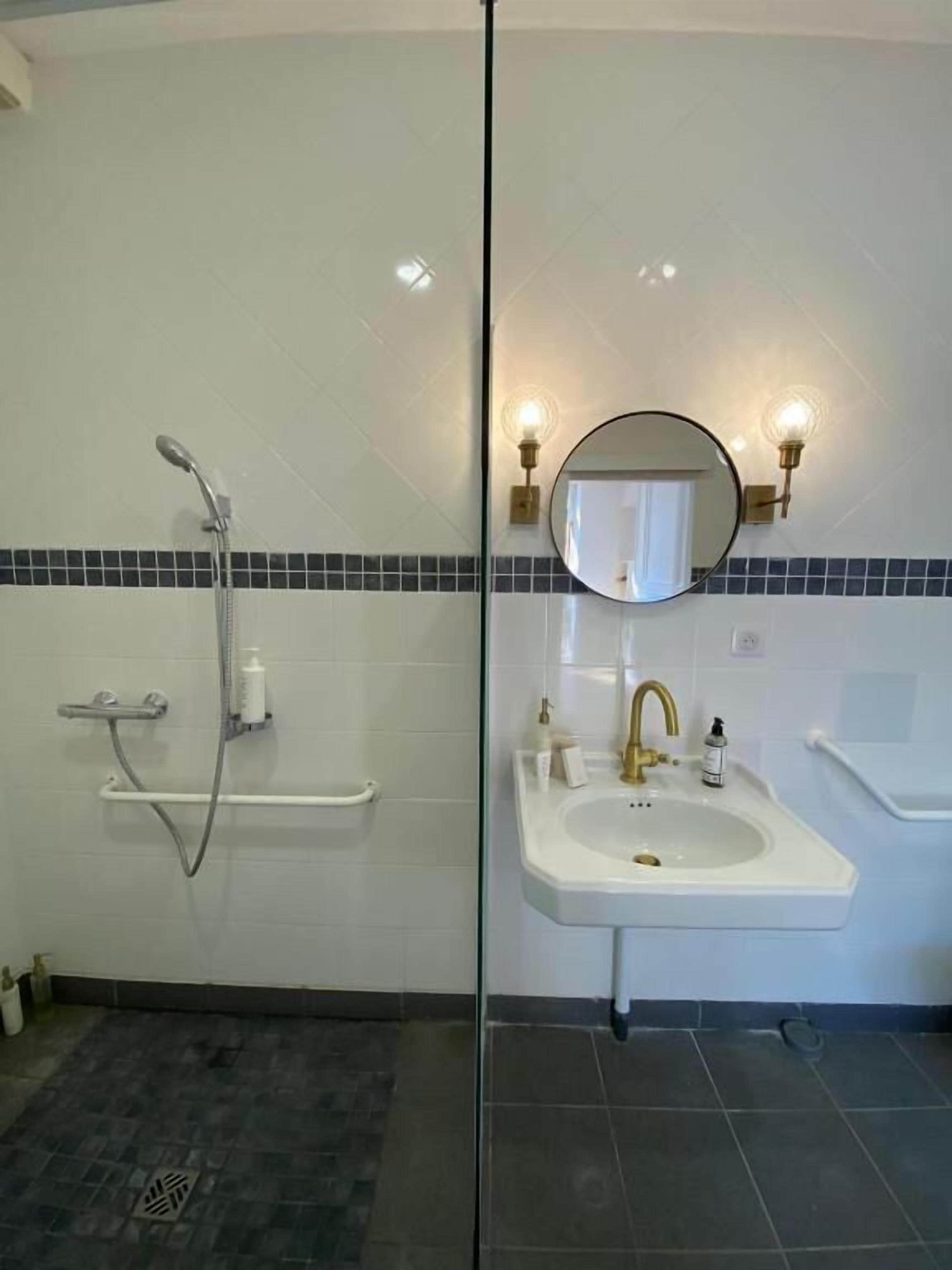 Une salle de bain avec une douche, un lavabo et un miroir.