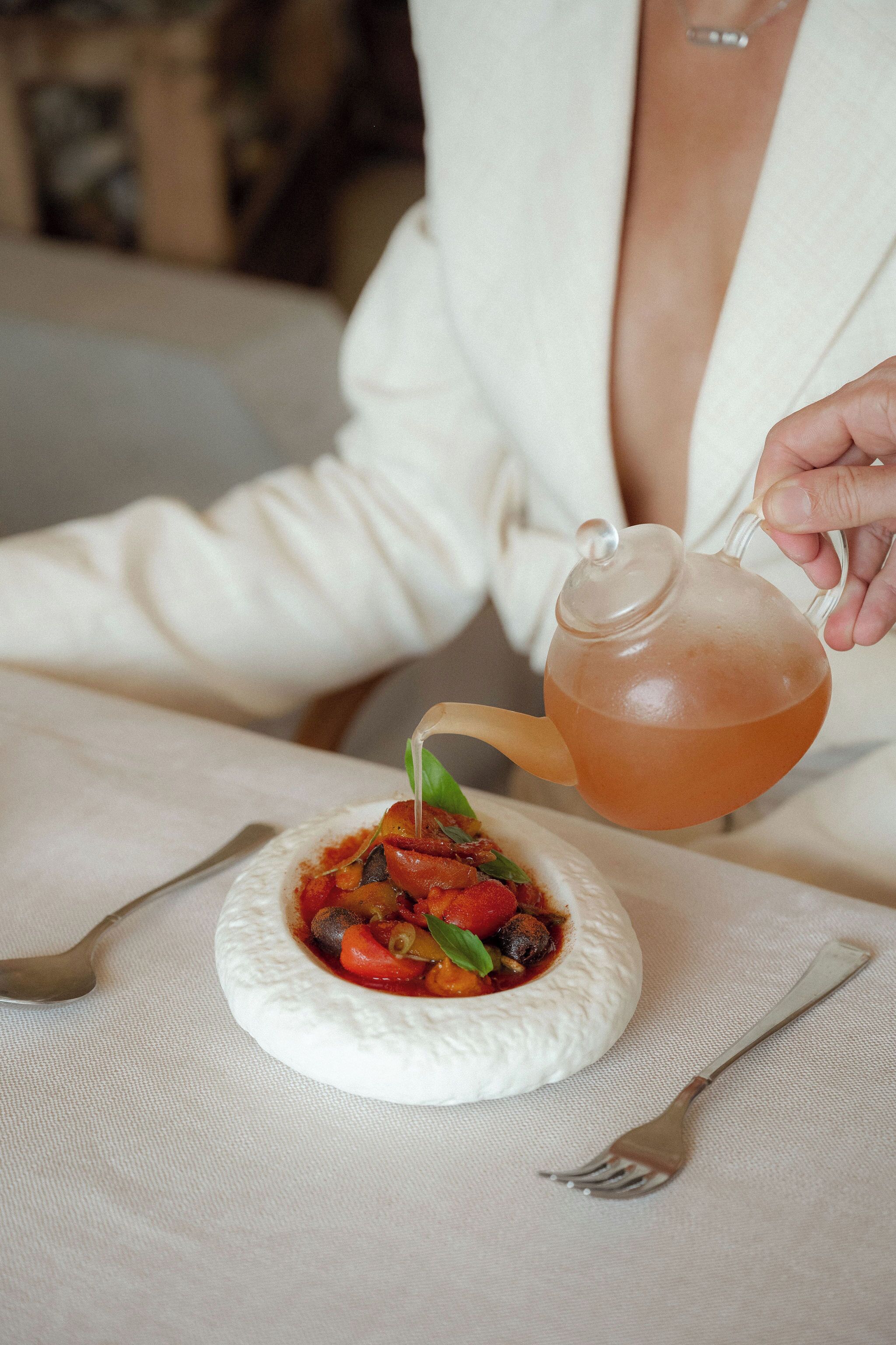 A person pouring tea into a bowl with a white interior.