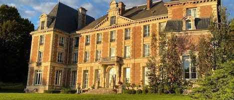 A large, historic building with a symmetrical facade, multiple windows, and a prominent tower.