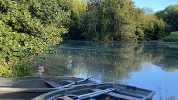 Una fila de barcos atados a un muelle, junto a un río tranquilo, rodeado de vegetación exuberante.