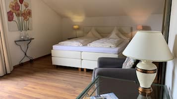 Un dormitorio con cama, mesita de noche, lámpara y una revista sobre una mesa de vidrio.