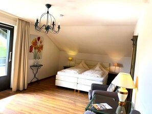 A hotel room with a bed, a desk, a chair, a lamp, and a chandelier. - Hotel garni Bellevue (Bad Fuessing)