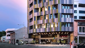 A multi-story hotel with a modern design, featuring balconies and a central entrance with a covered area. - Tido Hostel Penang (George Town)