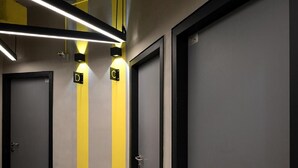 A hallway with doors marked 'D' and 'C', illuminated by overhead lights. - Tido Hostel Penang (George Town)