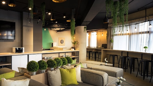 A modern interior with a sofa set, hanging plants, and a bar area. - Tido Hostel Penang (George Town)