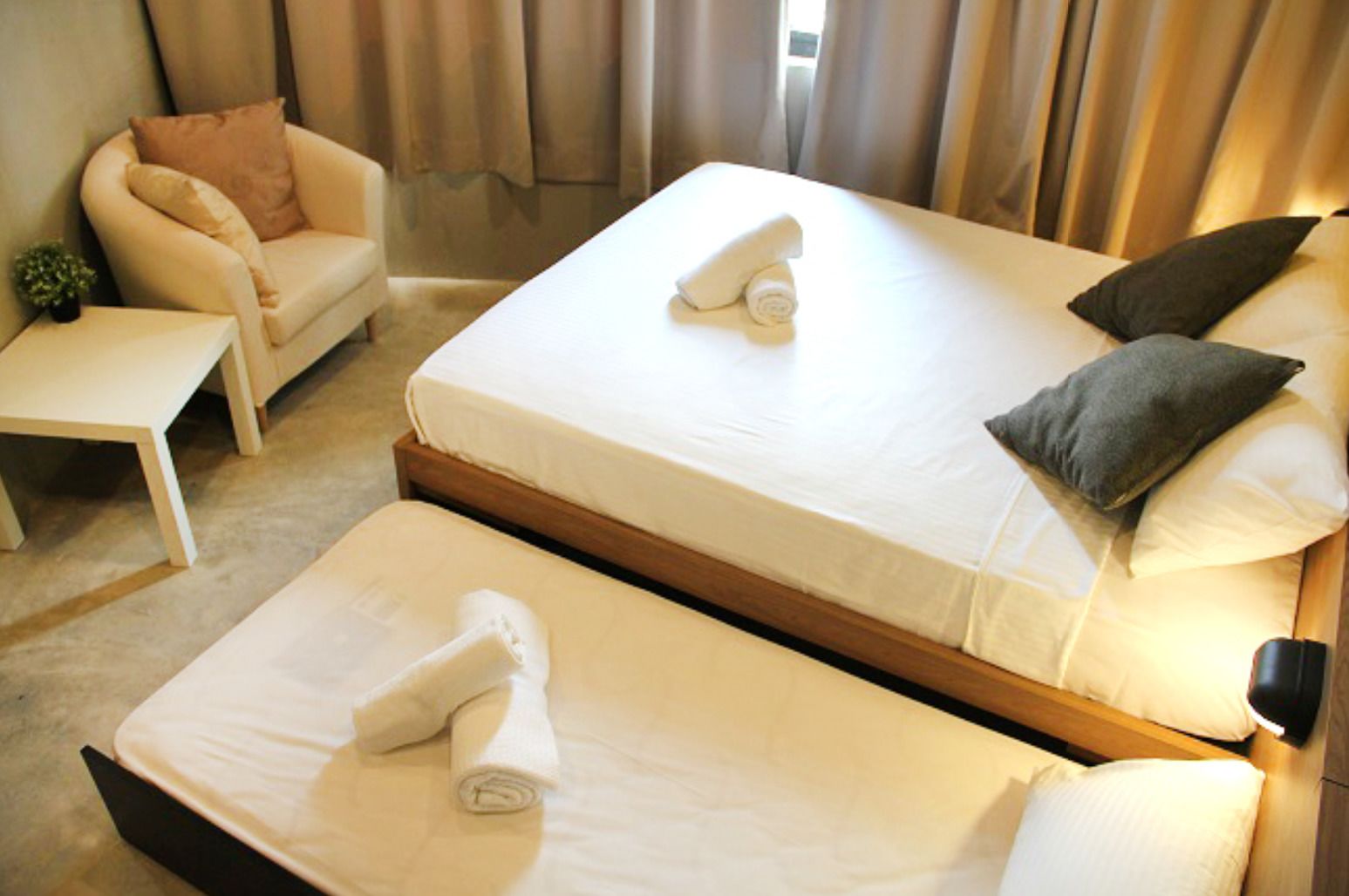 A hotel room with two beds, a sofa, a small table, and a window with curtains.