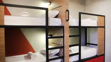 A bunk bed room with wooden headboards, a red cabinet, and a wall-mounted light.