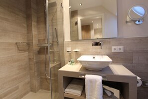 A modern bathroom with a glass shower enclosure, a large mirror, and a vessel sink.