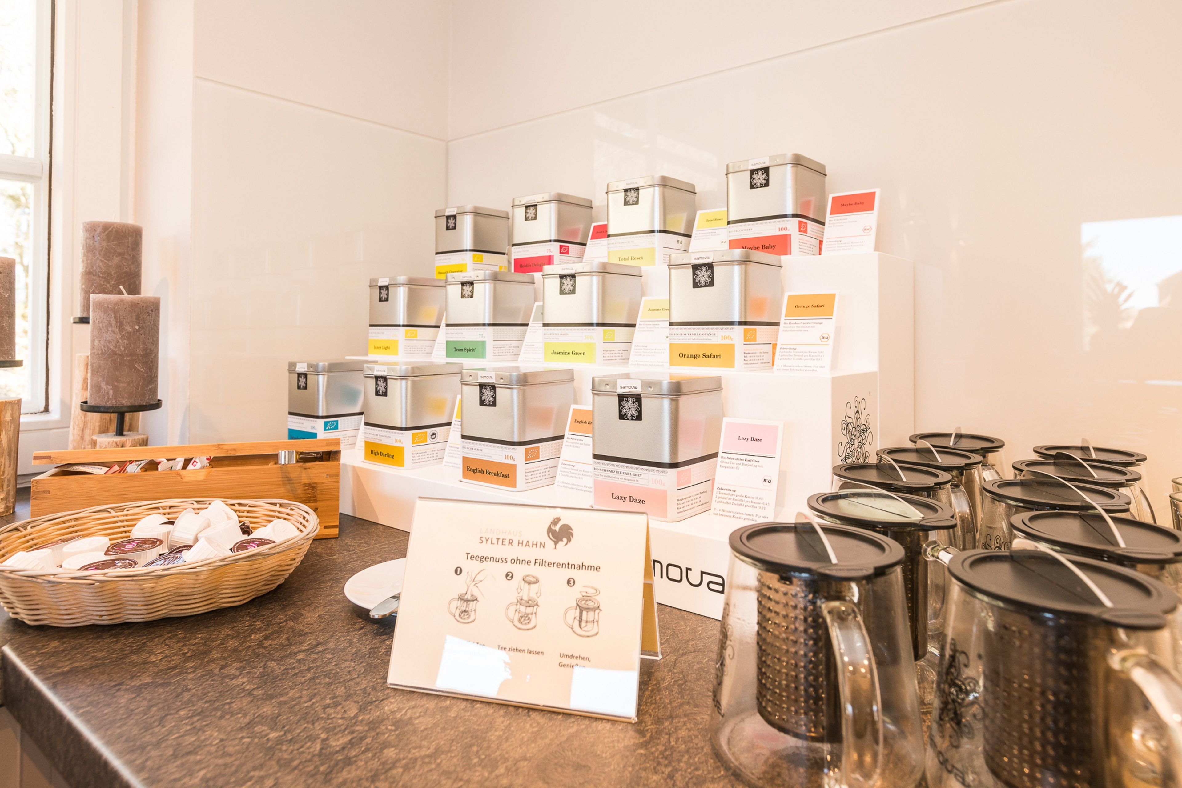 Exhibición de productos de té con etiquetas y un cartel en alemán.