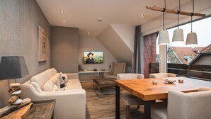 Ett modernt vardagsrum med en soffa, ett soffbord och ett matbord, en tv och utsikt över staden genom stora fönster.