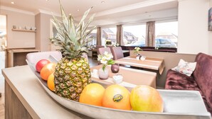 En fruktskål står på en bänk med en ananas, apelsiner och en citron i.