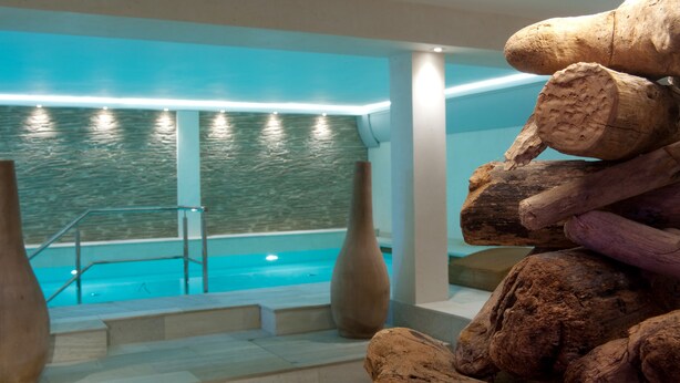 Ett spaområde med en pool, en stenmur och träskulpturer.