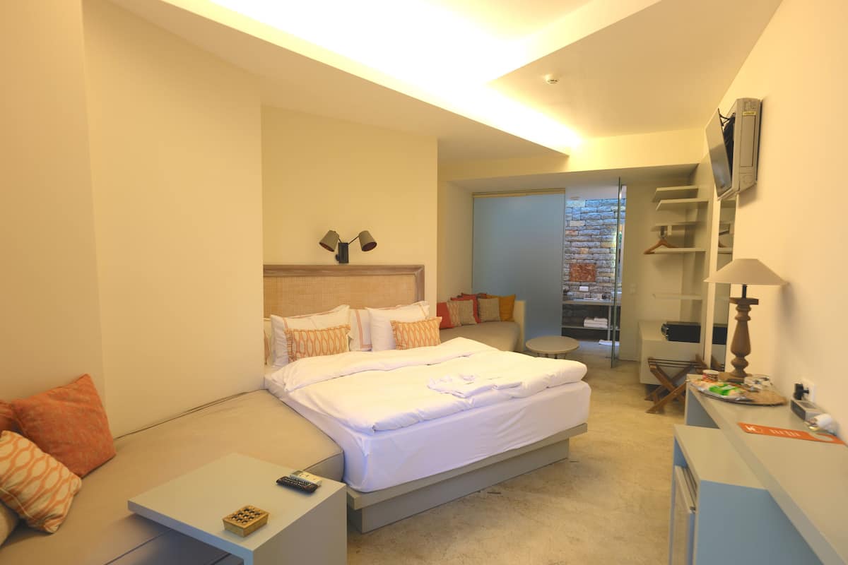 Una habitación de hotel moderna con una cama grande, mesitas de noche, un escritorio y televisión integrada.