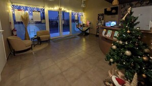Un vestíbulo amplio con un gran ventanal, un árbol de Navidad y un mostrador de recepción.