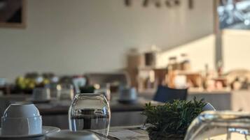 A breakfast setting with a wall sign reading "BREAKFAST FAST" and a table with cups, a glass, and a small plant.