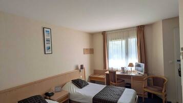 Une chambre d’hôtel avec deux lits, un bureau, une chaise, une télévision et une fenêtre avec des rideaux.