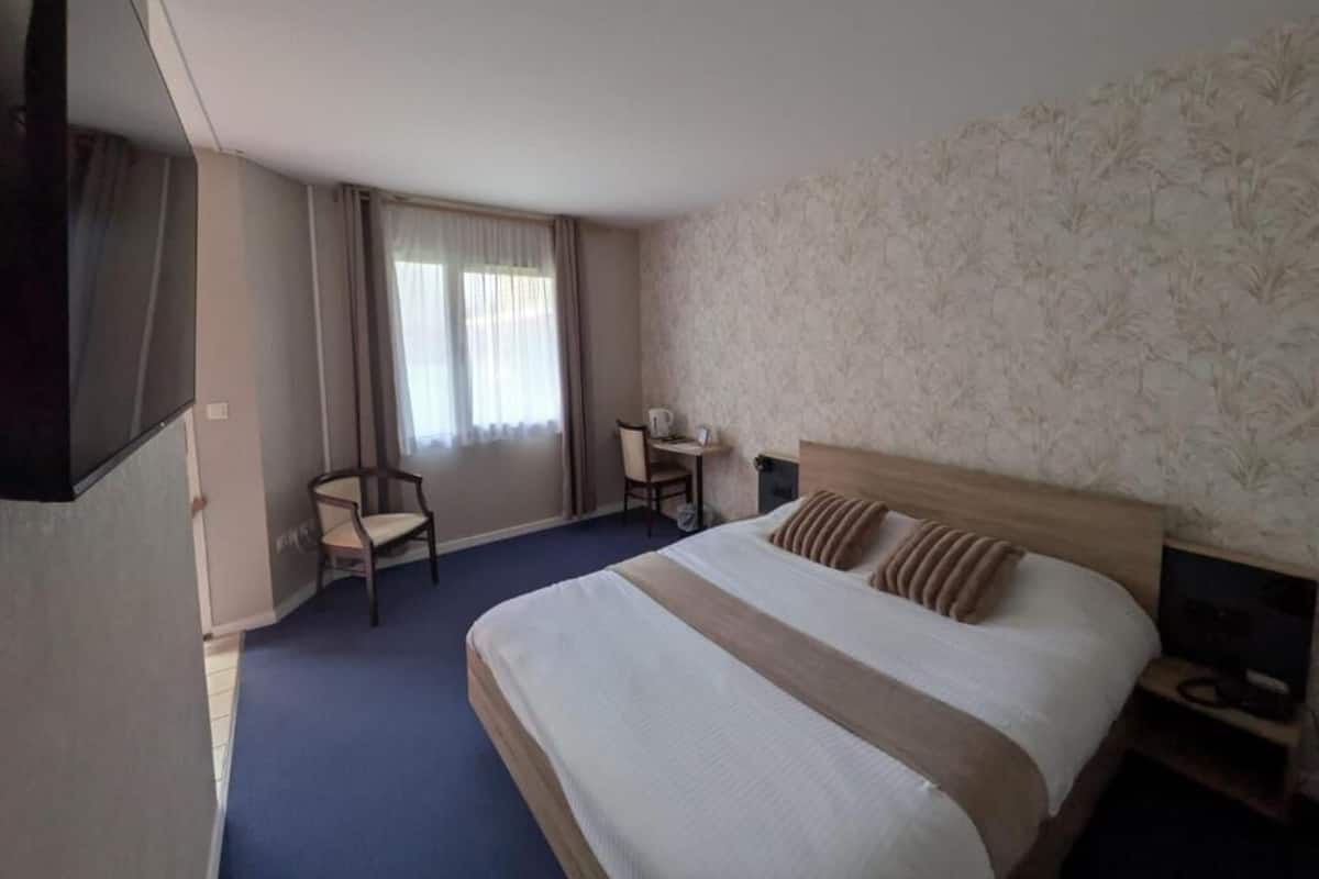 Ein Hotelzimmer mit einem großen Bett, einem Schreibtisch, einem Sessel und einem Fernseher.